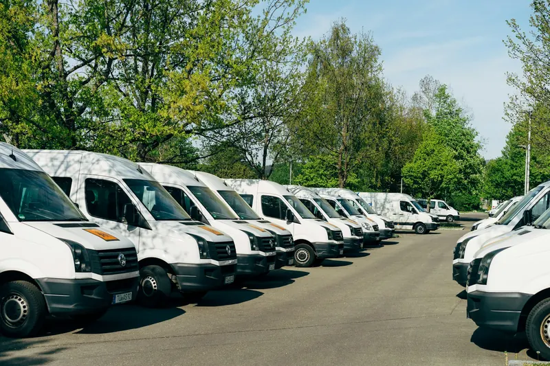 Reihe weisser Firmenbusse auf einem Parkplatz