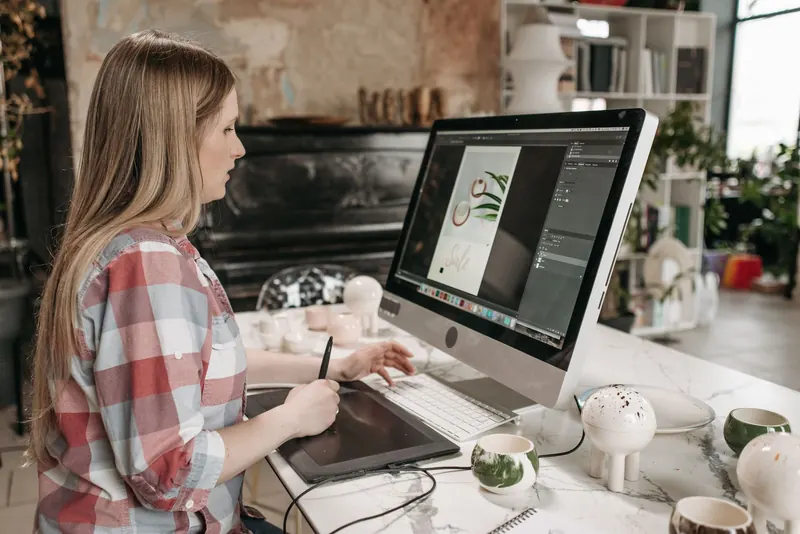 Gestalterin arbeitet am Bildschirm mit dem Grafiktablett an einem Entwurf